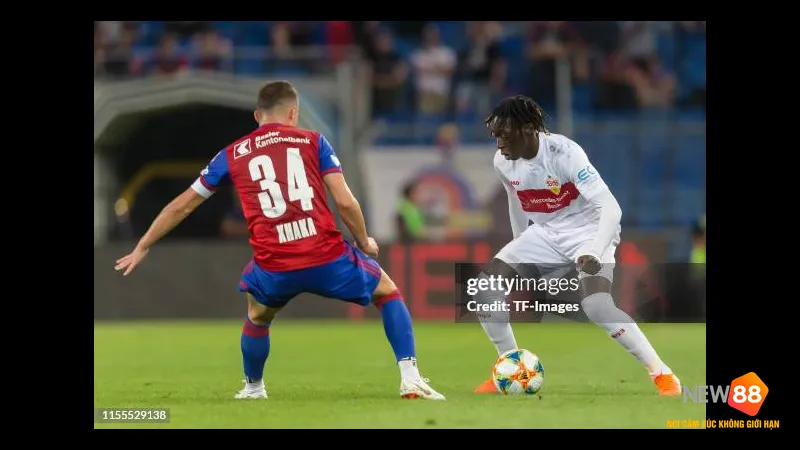 Cầu thủ Basel đi b&oacute;ng qua cầu thủ Stuttgart trước sự chặn đứng của hậu vệ đối phương